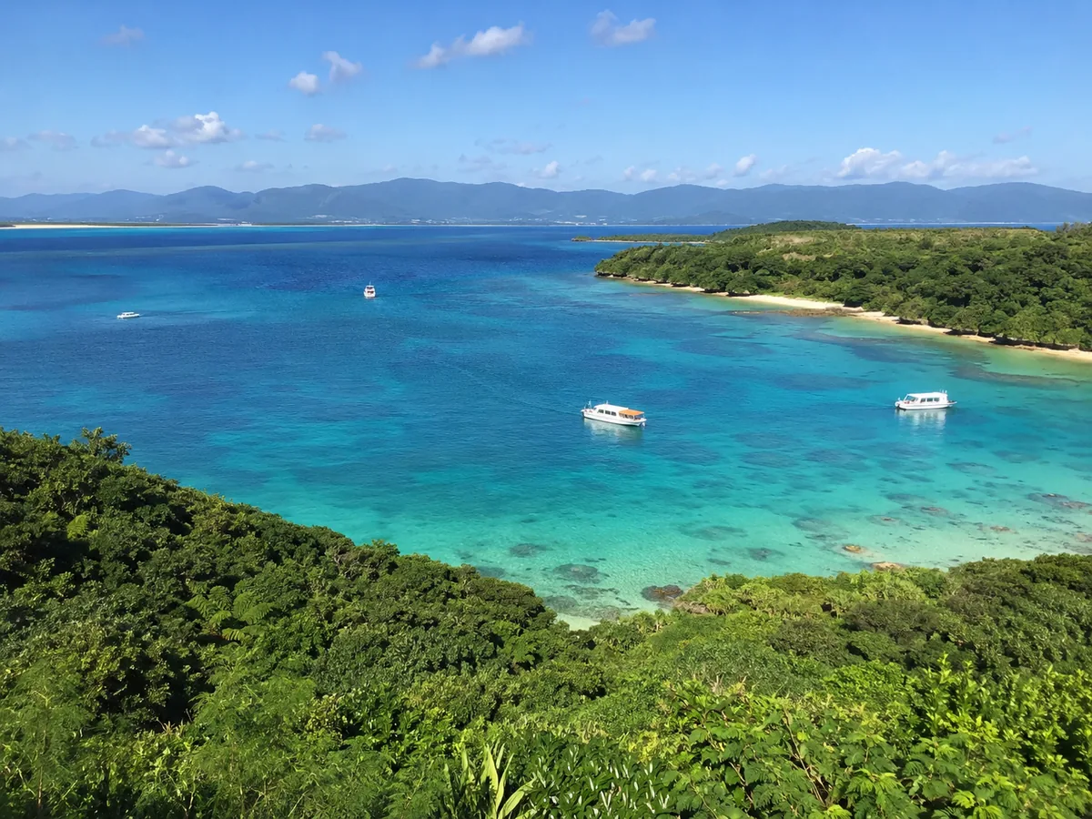 浅瀬から沖へ色が変わる入り江。グラスボートが数隻浮かんでいる